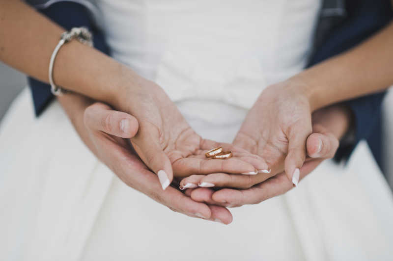 新郎捧着新娘的手里的结婚戒指