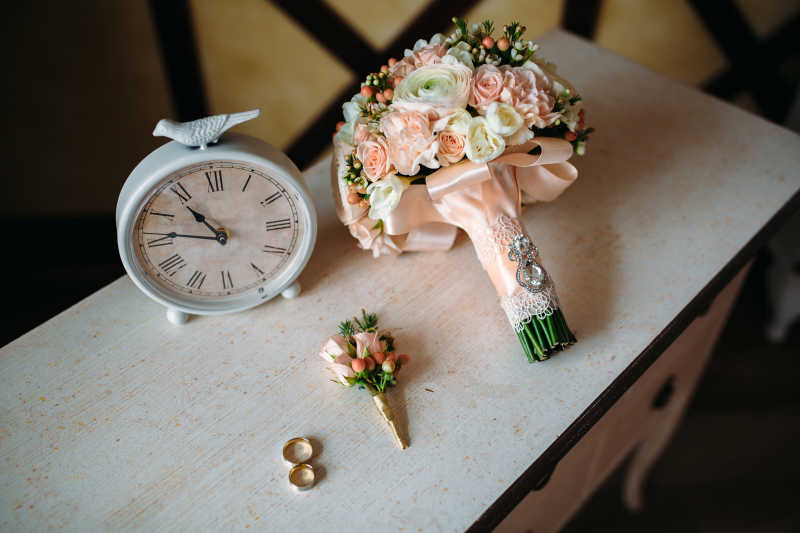 白色纹理的桌子上的捧花胸花和戒指