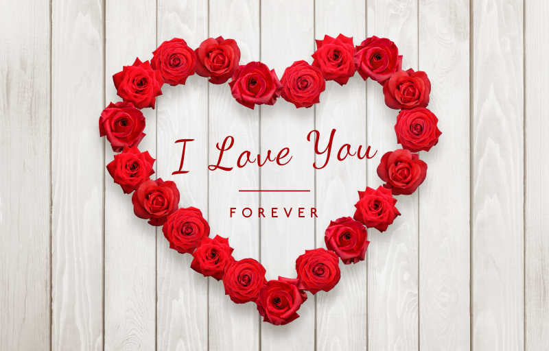 木制背景上玫瑰摆成爱心状中间ILVEYOU