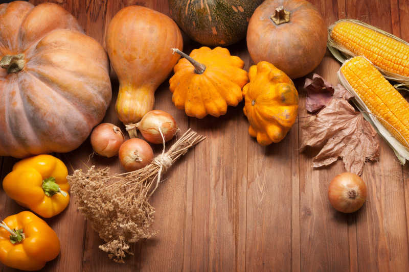 感恩节木制餐桌上的南瓜和洋葱甜椒