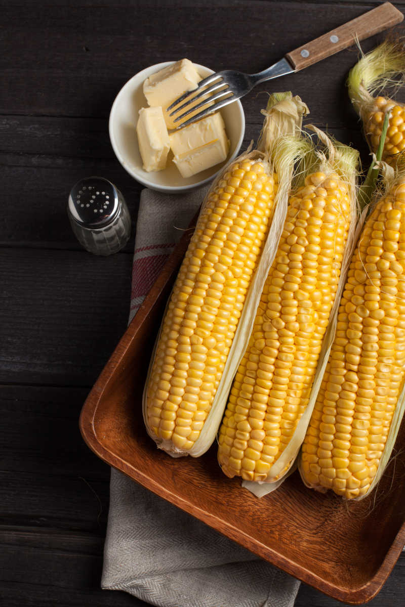 新鲜的玉米在木桌上还有黄油和盐