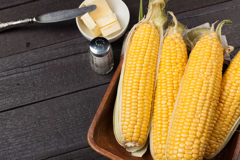 褐色木制桌上的新鲜玉米棒
