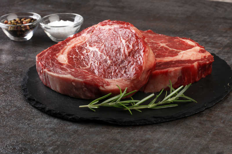 深色背景下的生牛排和迷迭香