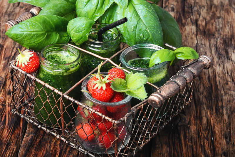 铁篮子里的罗勒叶子菠菜汁和新鲜草莓