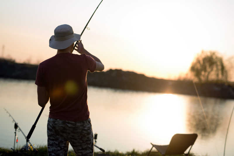 年轻钓鱼爱好者在池塘里钓鱼