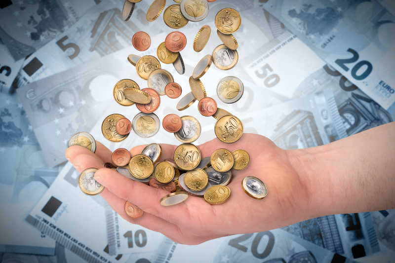 钞票背景上手里的欧元硬币