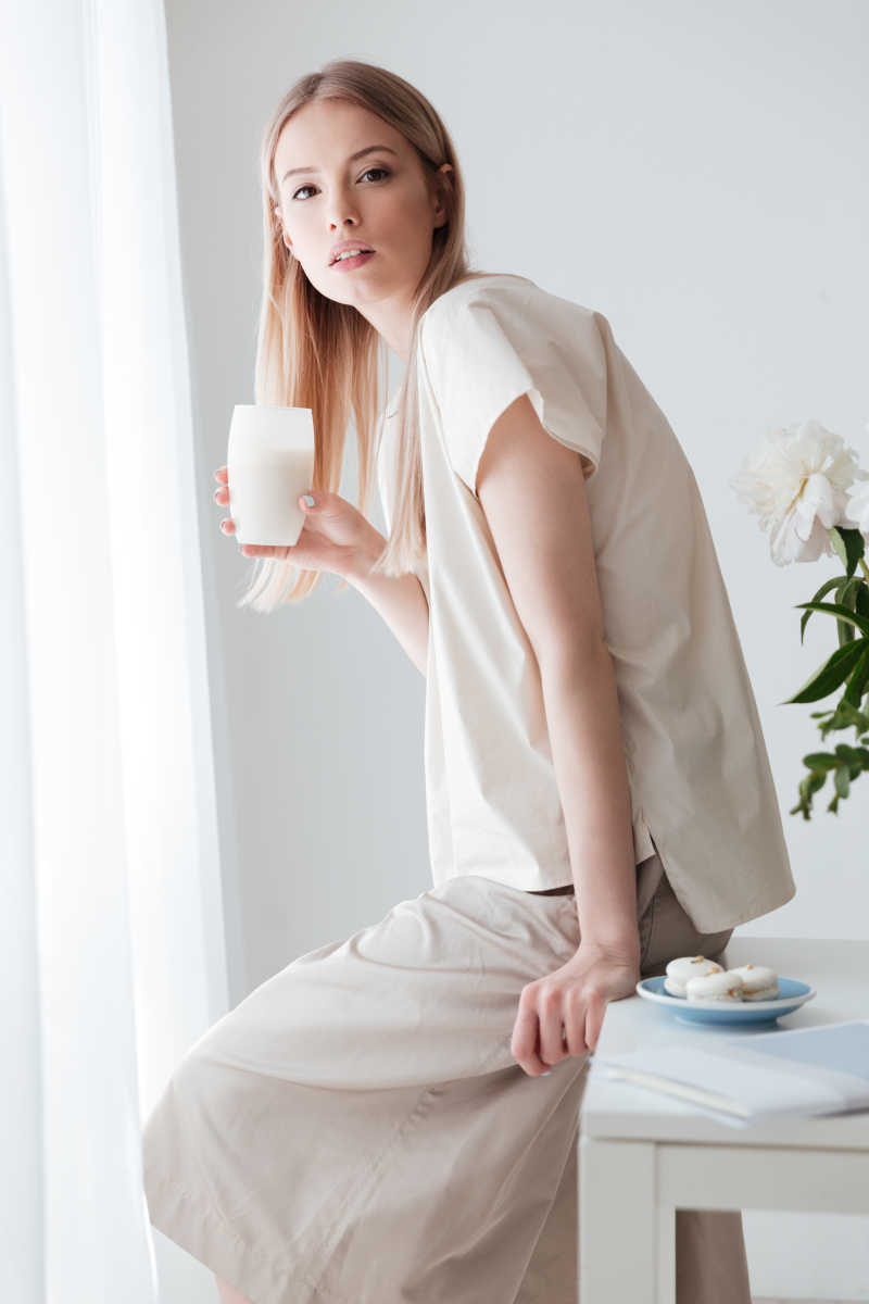 坐在桌上和牛奶的舒适年轻人