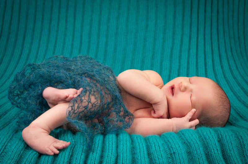 绿色针织背景下的睡着的婴儿