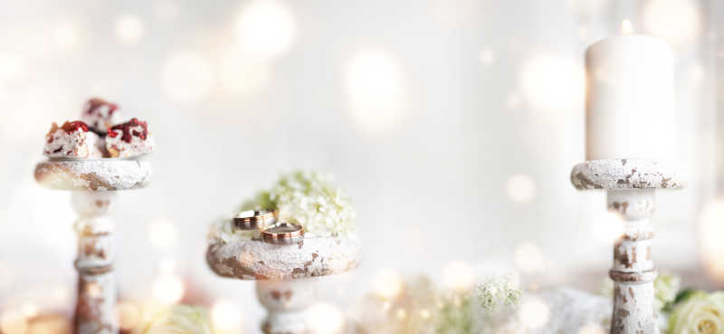 背景虚化下的三个烛台蜡烛对戒甜点特写