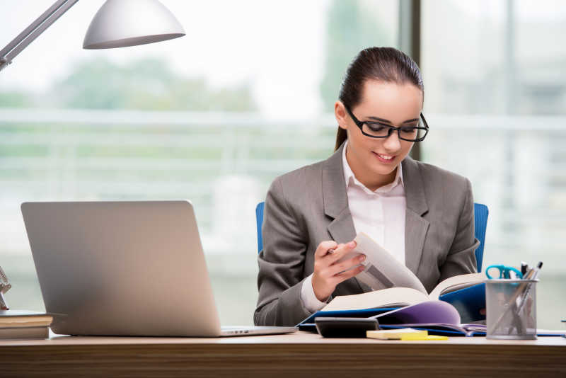 办公桌旁看着书的女商人