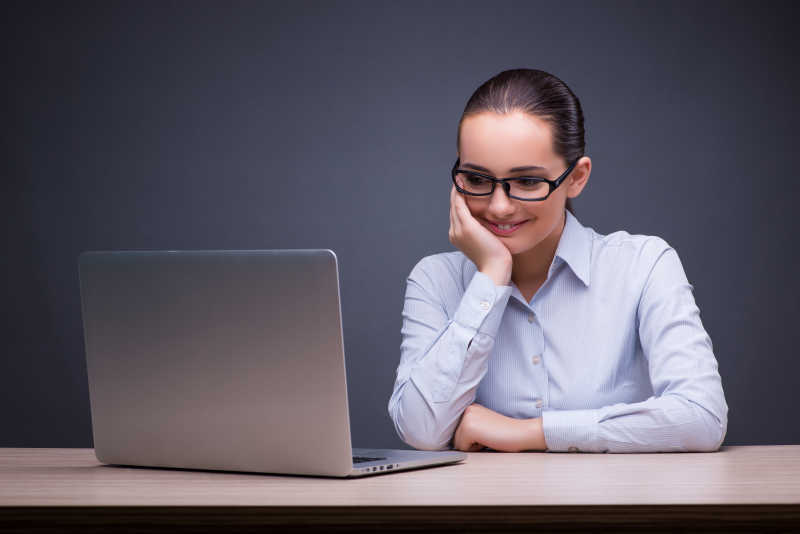 年轻的商人在她的办公桌上看着笔记本电脑