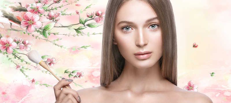 手拿化妆刷的年美丽轻女孩已经完美的妆容