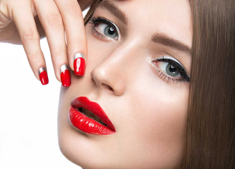红色美甲和红色口红的脸部彩妆特写