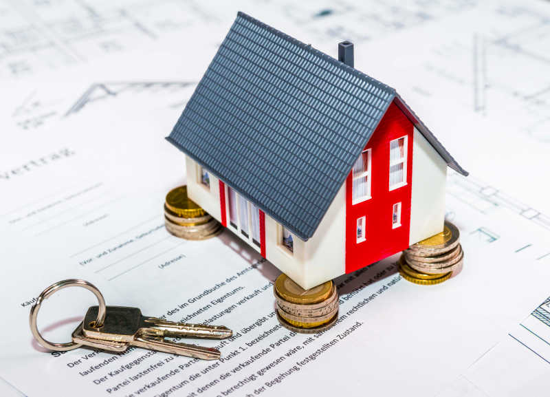 架在硬币上的房屋模型和钥匙