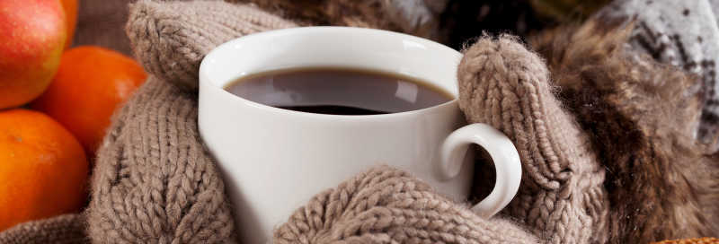 戴有手套的双手捧着咖啡杯