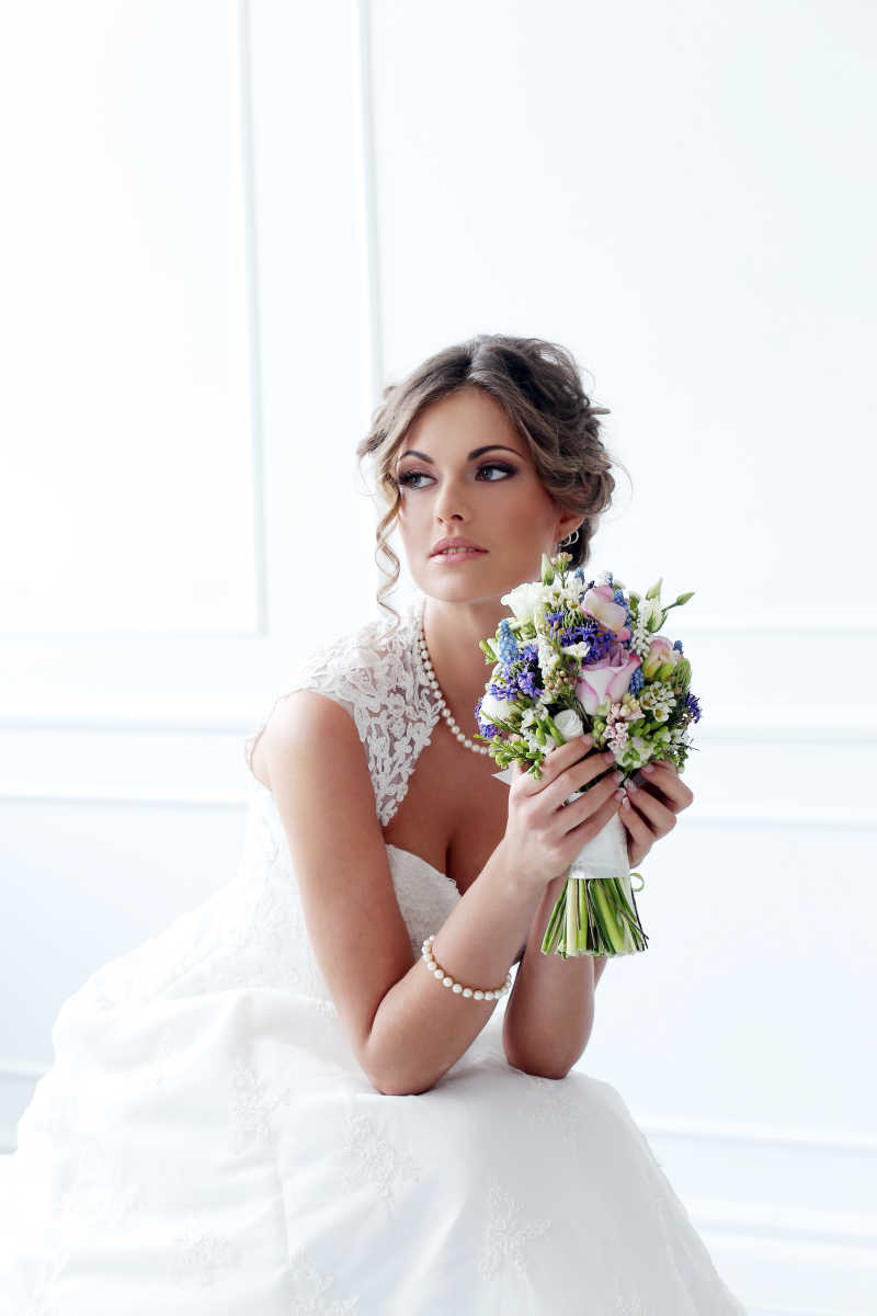 坐着的穿着洁白婚纱捧着捧花的新娘