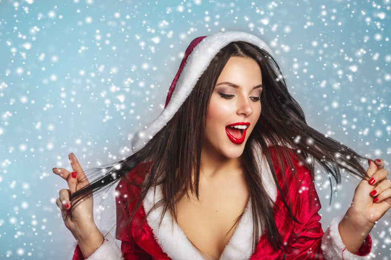 雪花背景中的穿着圣诞老人服装的圣诞美女