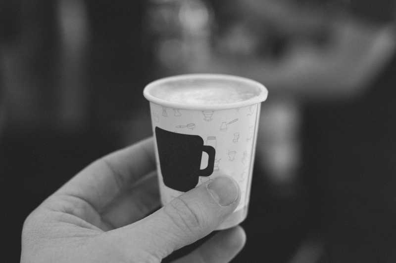 手拿装满咖啡的纸杯特写