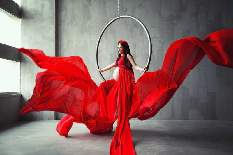 穿着红色长礼服的美丽孕妇