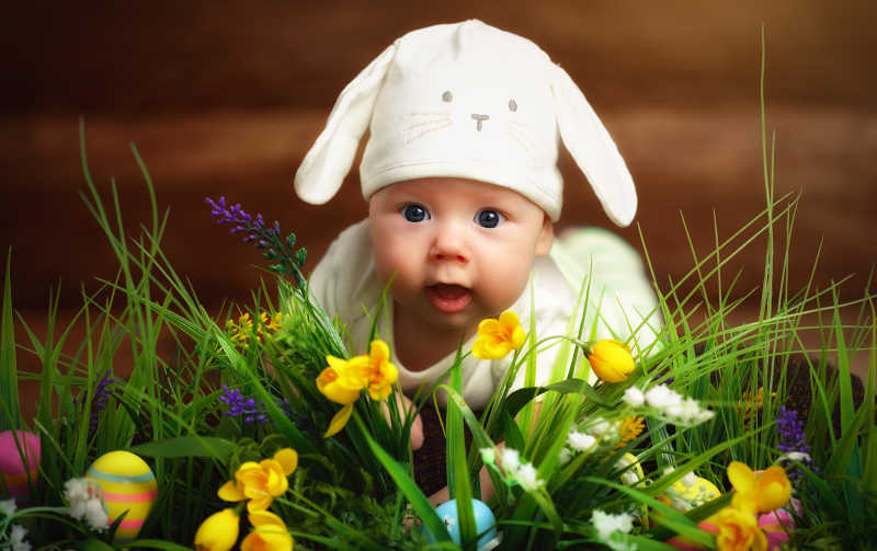 快乐的小宝宝打扮成复活节兔子躺在草地上