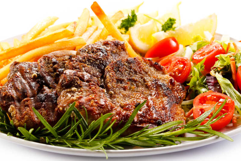 盘子里的烤牛排炸薯条和蔬菜配菜特写