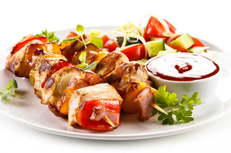 盘子里的烤羊肉串和蔬菜配菜