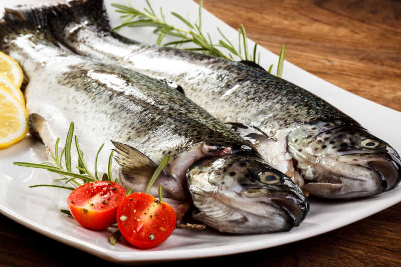 盘子里的新鲜的生鳟鱼和小番茄迷迭香特写