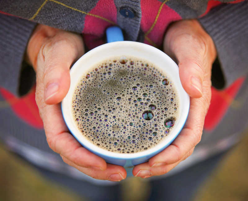 双手拿一杯咖啡的女人