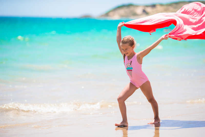 在热带海滩享受白色沙滩和碧绿海水享受的小女孩