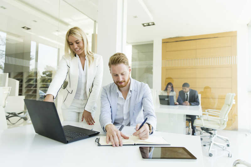 办公室做笔记的男人和看电脑数据的女人