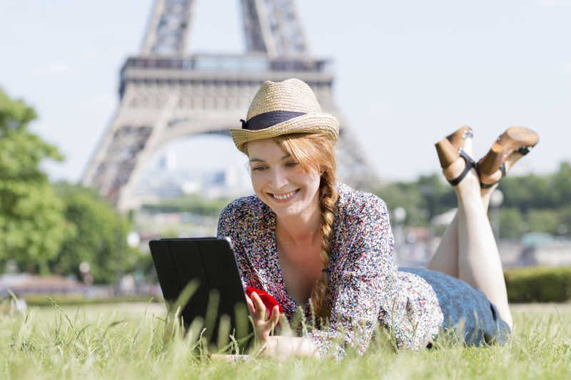 趴在草地里看着平板电脑的美女