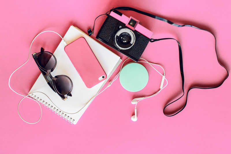 粉红色背景下的相机手机用品