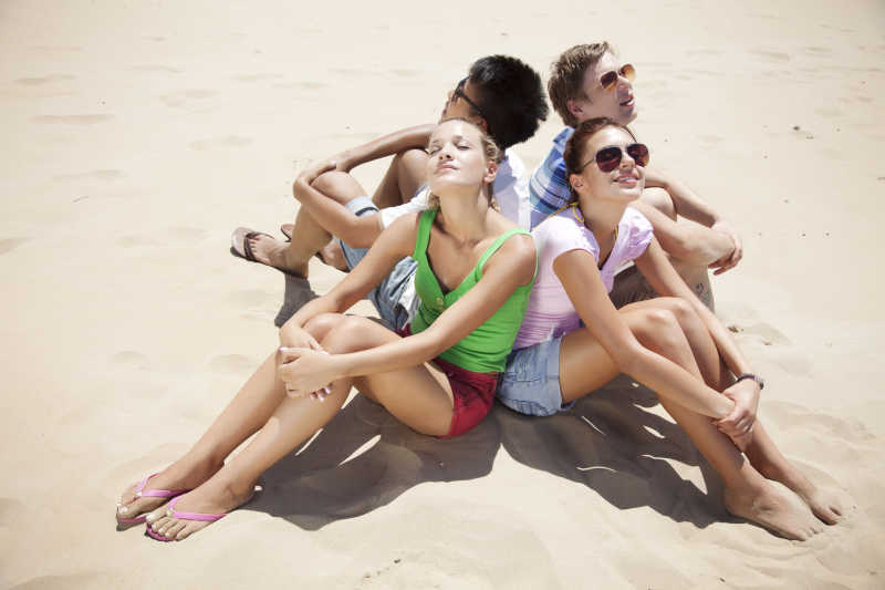 四个年轻人坐在沙滩上