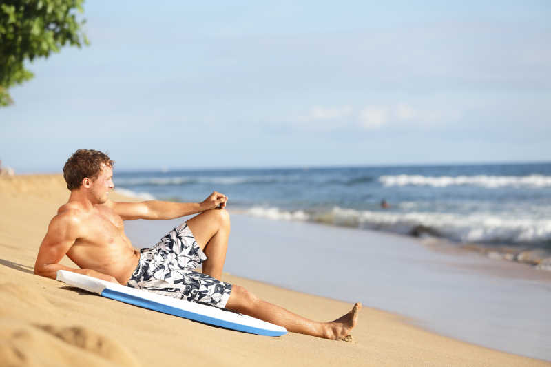 海滩男人在美丽的海滩冲浪后放松