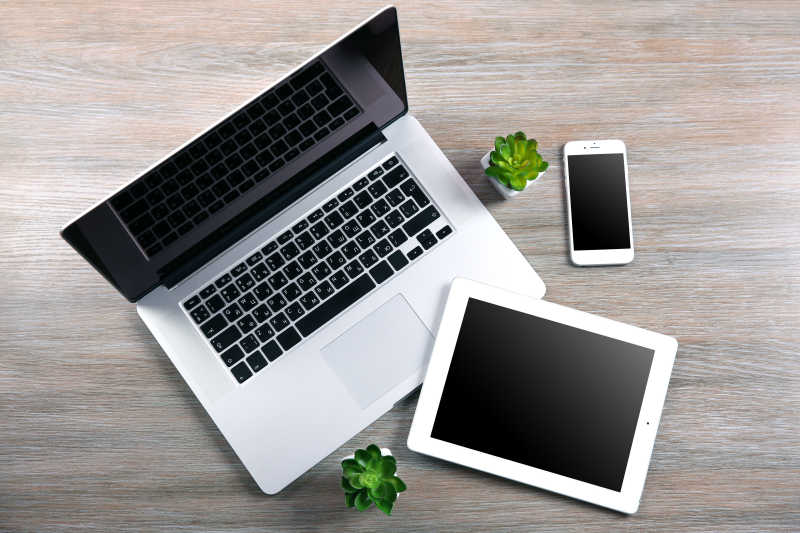 现代笔记本电脑智能手机和桌上有绿色小植物的平板电脑
