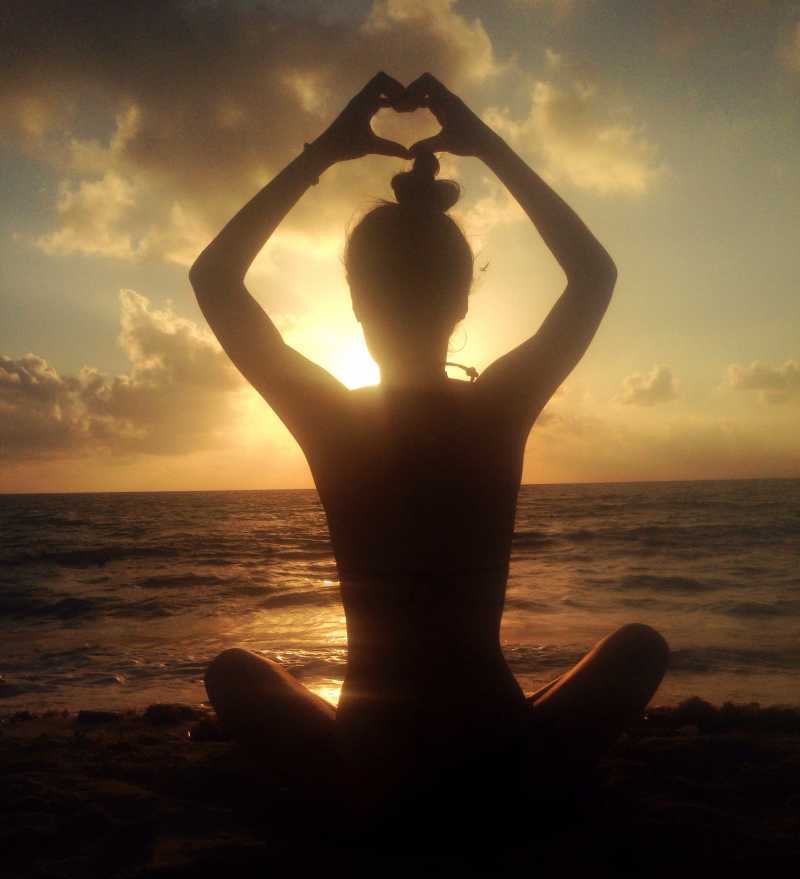 坐在海边日出下的冥想的美女背影特写