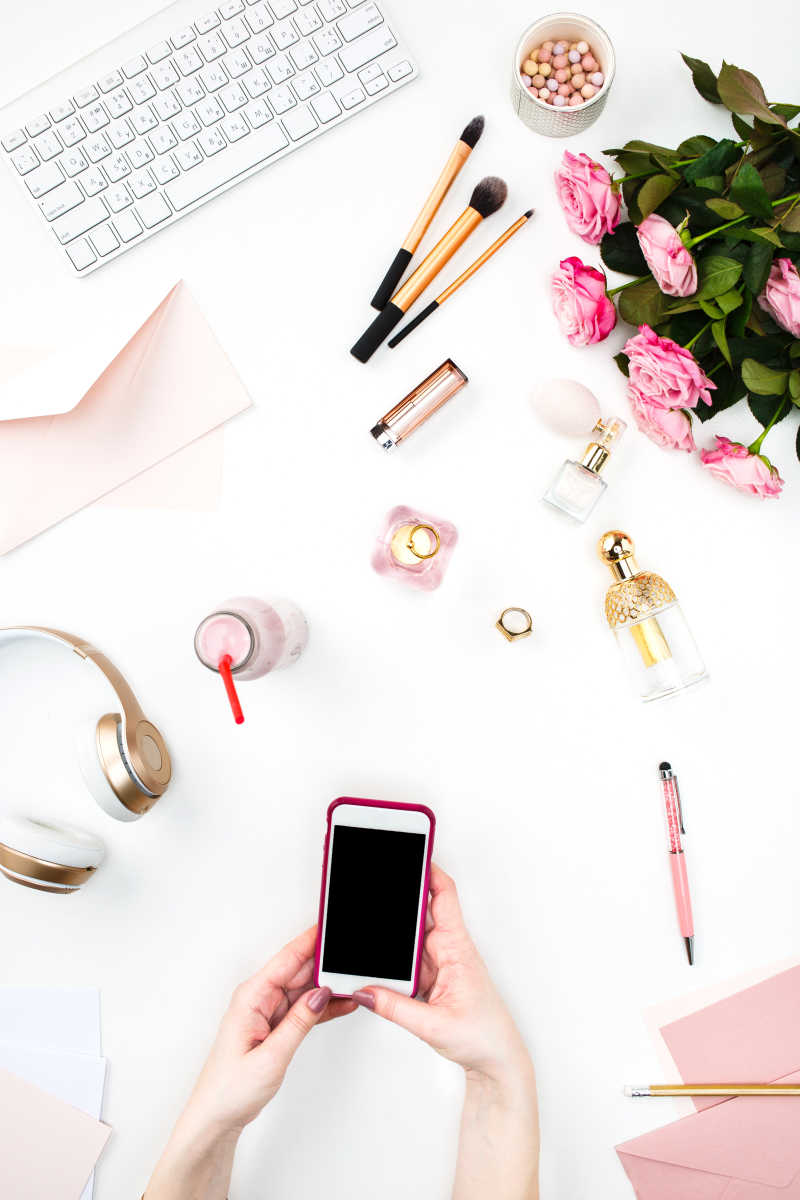 女性手拿智能手机和旁边的日常用品