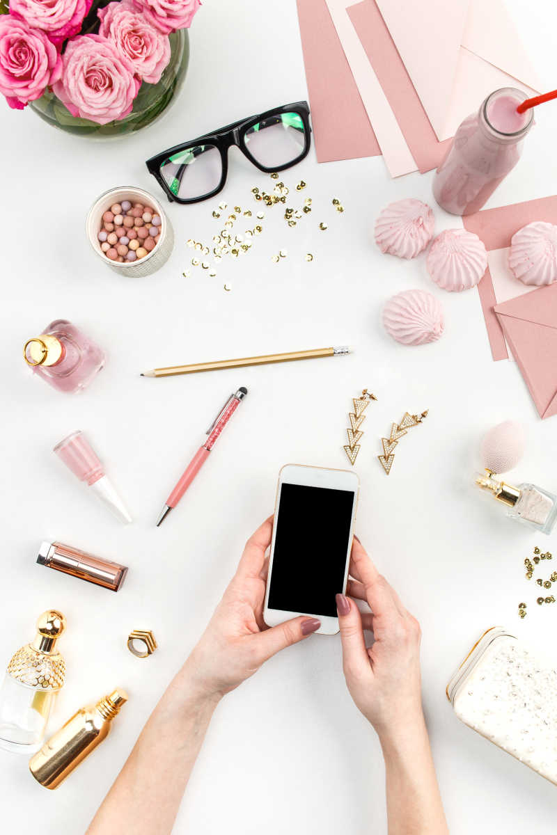 手拿智能手机和旁边的化妆品