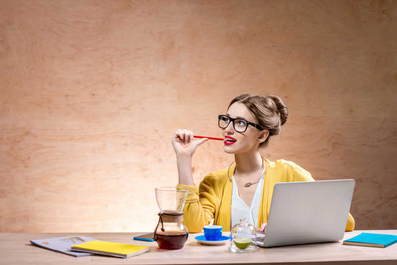 带着黑框眼镜嘴咬铅笔的玩笔记本的少女