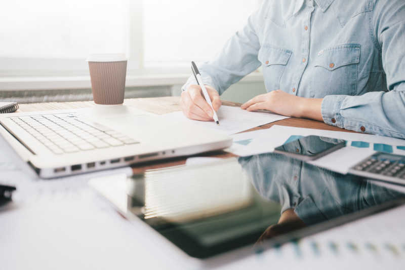 在办公室用笔记录数据的女商人