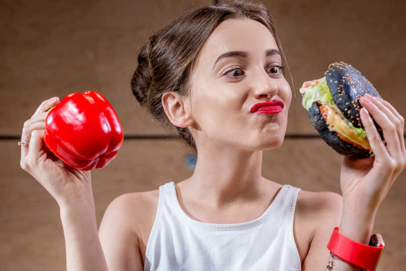 拿着汉堡和新鲜胡椒的年轻女人