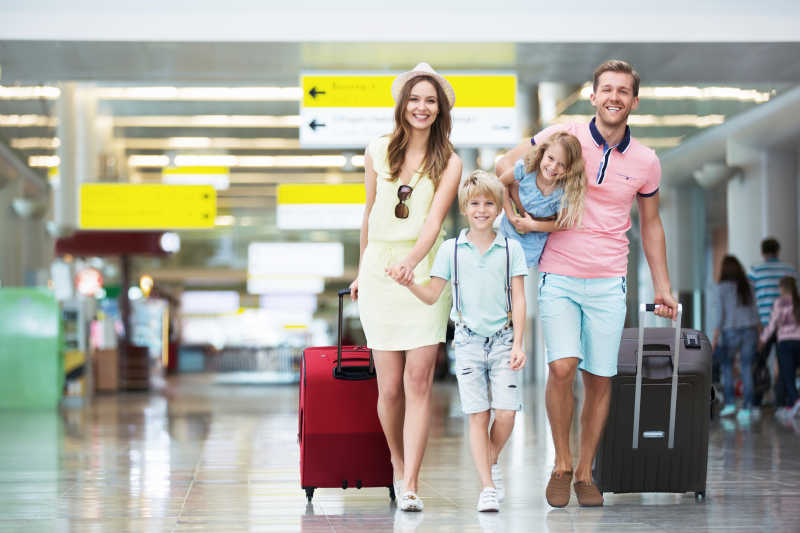在机场带着手提箱的幸福家庭