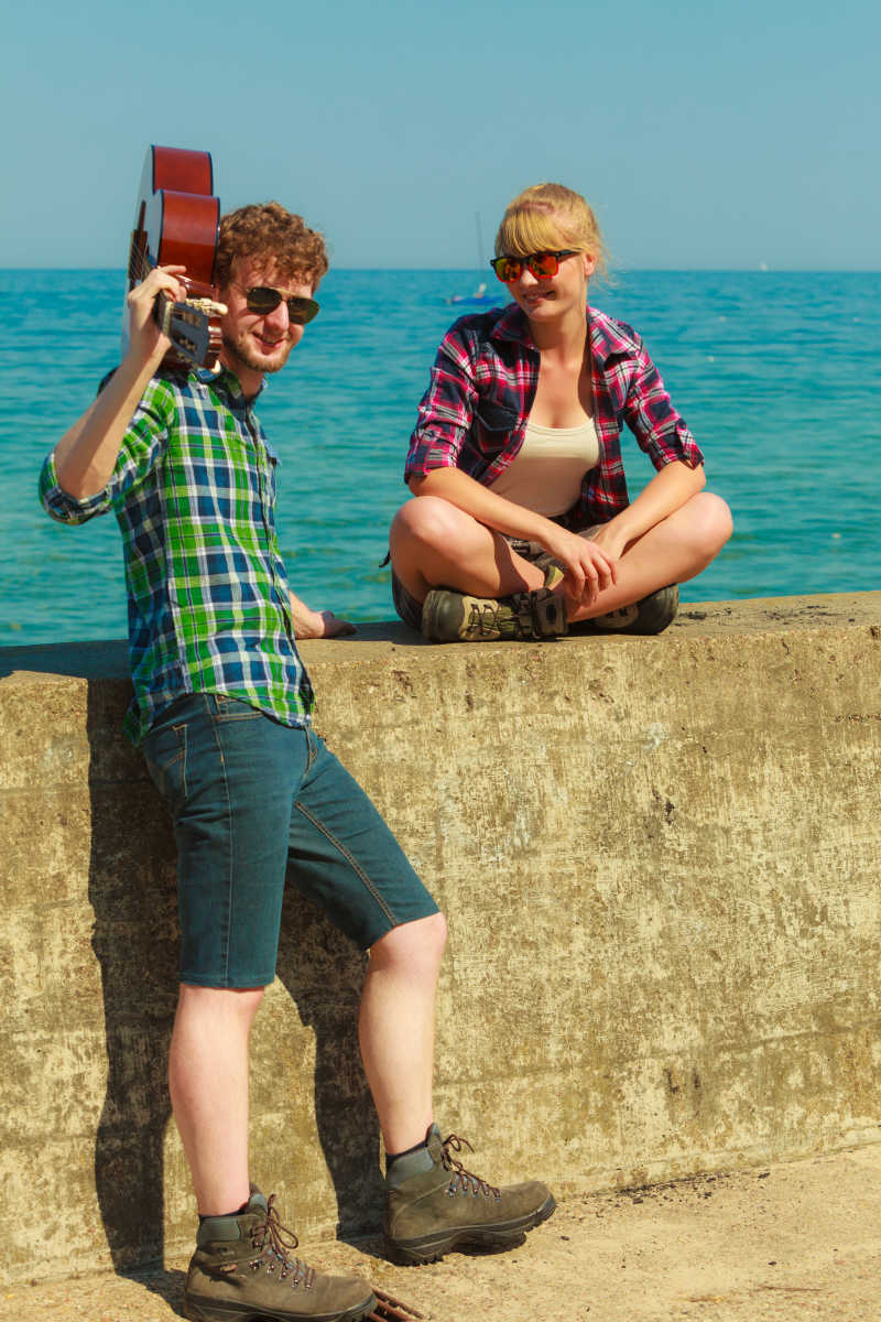 拿着吉他年轻男女在海边约会