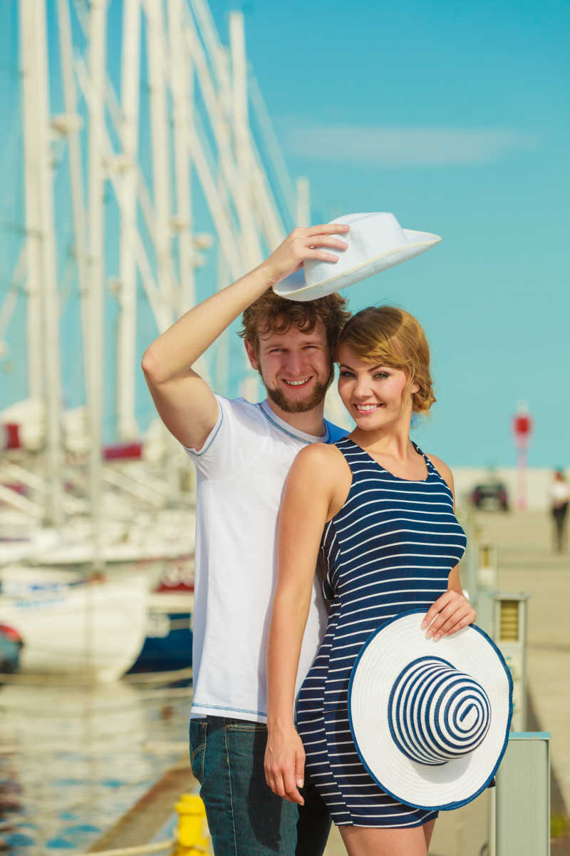 码头上的手拿帽子的游客夫妇