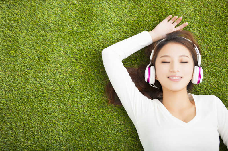 在草地上听音乐放松的女孩
