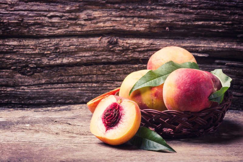 木背景下的摆在篮中的鲜桃