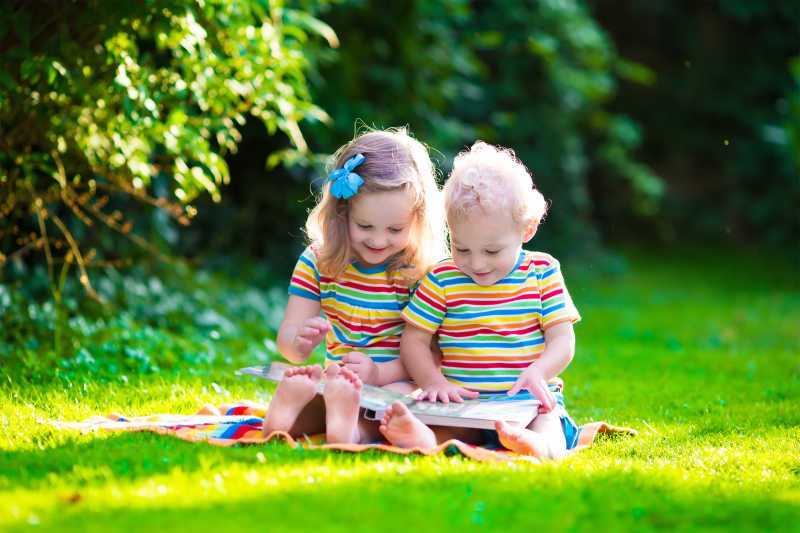 在夏日花园草坪里读书的孩子们