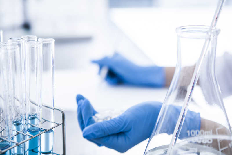 医学研究人员戴着蓝色橡胶手套记录药物