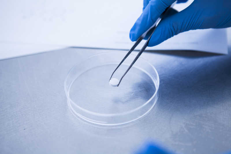 医学研究人员用镊子夹取药片
