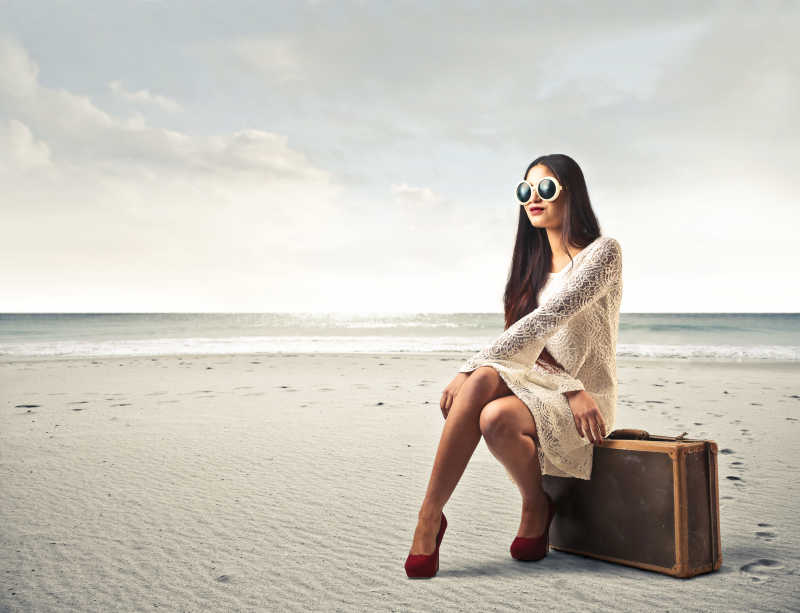 坐在海滩边的时尚美女